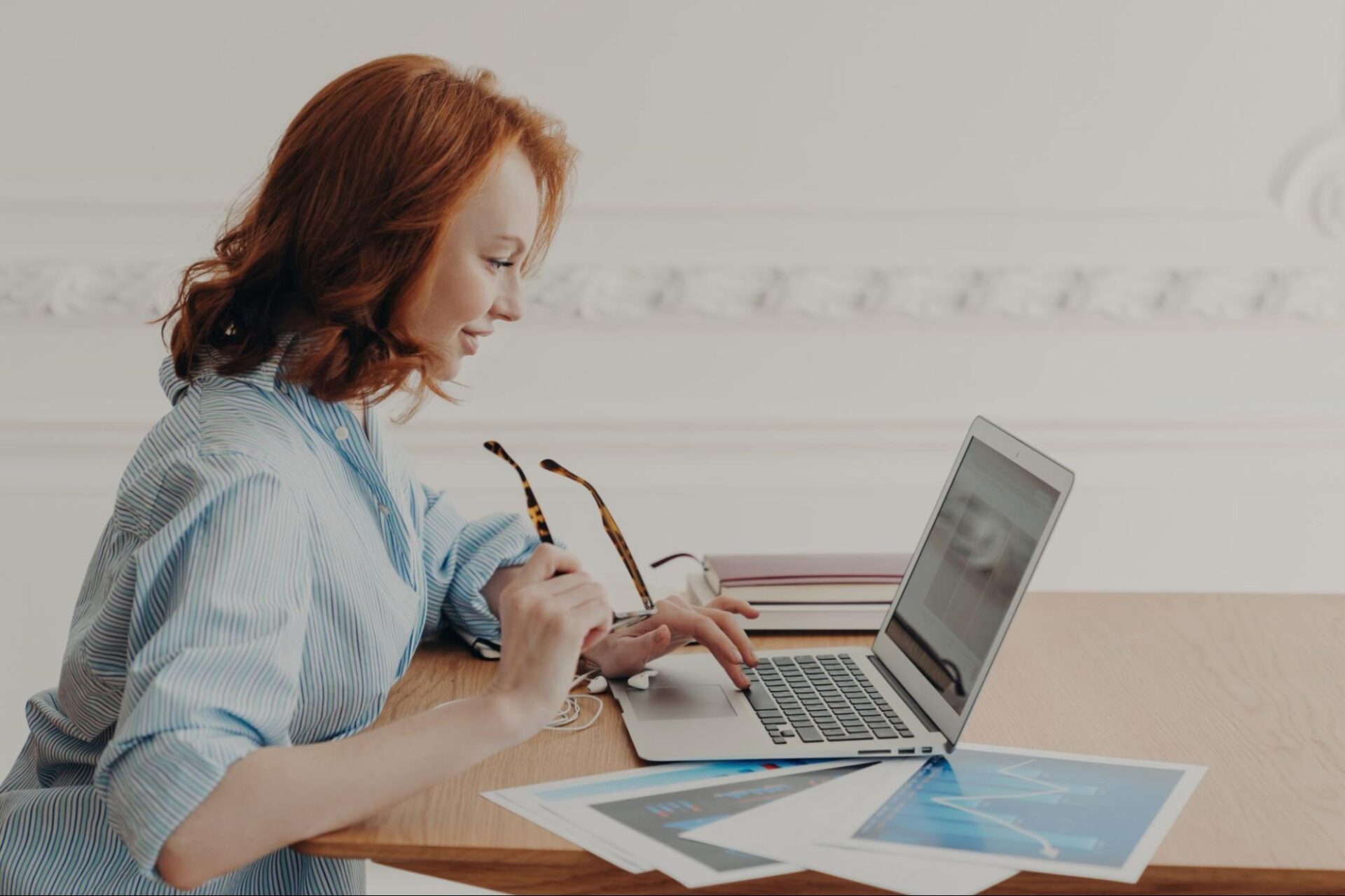A woman at a table using a laptop showcasing concentration in a bright and inviting environment